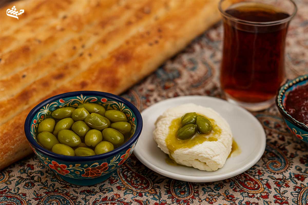 صبحانه ایرانی با نان بربری، سرشیر و مربای چاقاله پسته