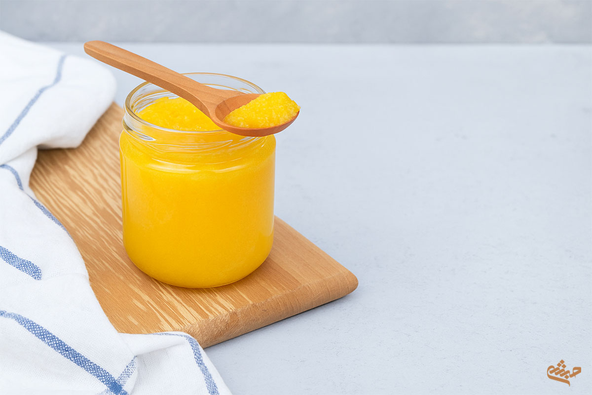 rustic ghee jar on wooden board with spoon